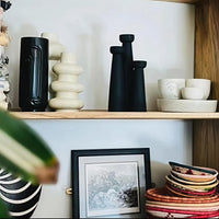 Shelves with decorative vases, cups, and a framed picture on a light-colored wall.