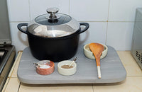 Black pot with a lid on a gray cutting board in a kitchen setting