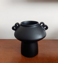 Black vase with two handles on a wooden surface