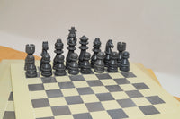 Set of black chess pieces on a checkered board with a plain background