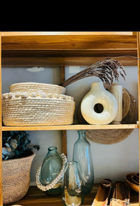 Decorative items on a wooden shelf including baskets, vases, and bottles.