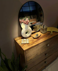 Wooden dresser with decorative items including a vase and mirror.