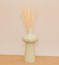 White vase with dried wheat on a beige background