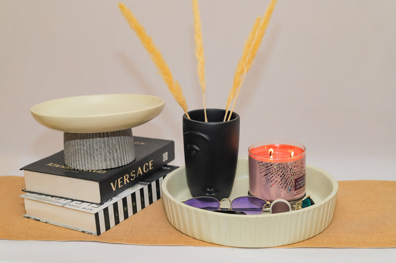 Decorative items including a candle, books, and a small plant on a tray with a plain background