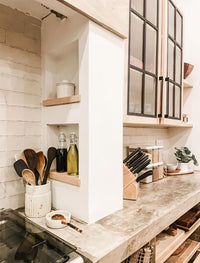 Modern kitchen with marble countertop, wooden shelves, and various kitchen utensils.