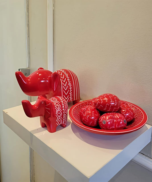 Red soapstone elephant and bowl set on a white surface with a neutral background