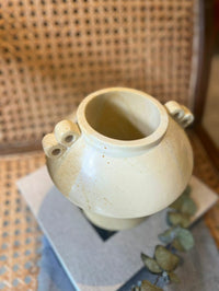 White ceramic vase with two handles on a textured surface