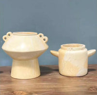 Two ceramic pots on a wooden surface with a blue background