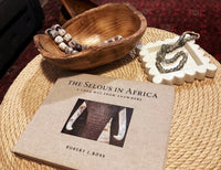 Book titled 'The Selous in Africa' by Robert J. Ross on a woven surface with a wooden bowl and decorative items.