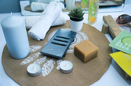 Candle, soap, and other items on a textured surface with a neutral background