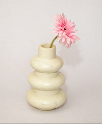 White vase with a pink flower on a light gray background