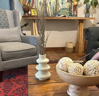Living room with gray sofa, decorative items on a wooden table, and colorful artwork.