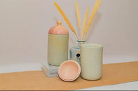 Set of pastel-colored ceramic items on a wooden surface with a neutral background