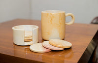 Marble-patterned mug with coasters on a wooden surface