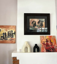 Framed artwork on a wall with sculptures and additional paintings below.