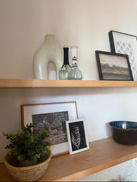 Wooden shelves with decorative items including vases, a plant, and framed pictures.